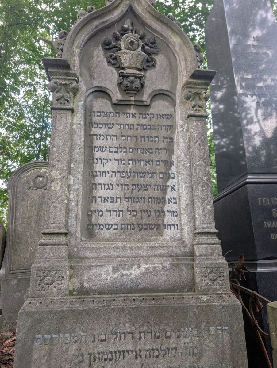 An ornate standing matzevah with a carved flower basket and full Hebrew inscription