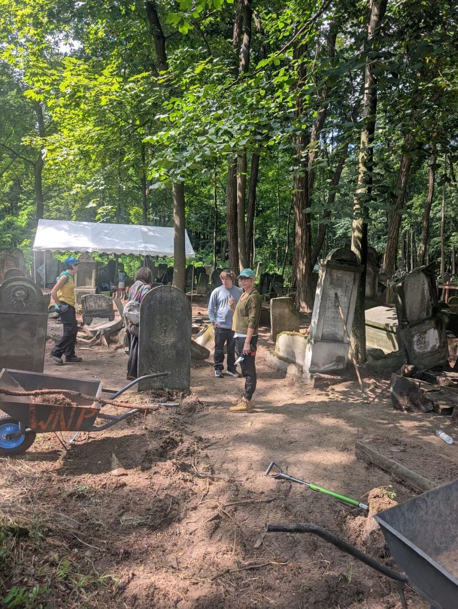 Volunteers working among headstones, wheelbarrows and a work tent behind